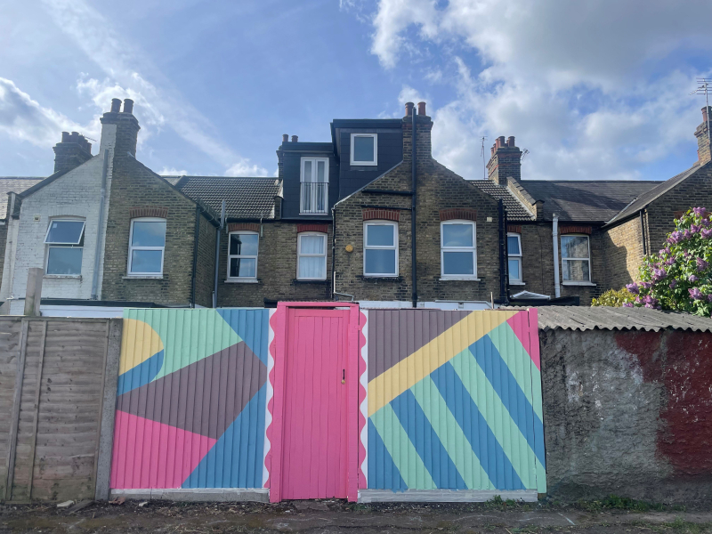 A wooden fence painted with a bright geometric pattern