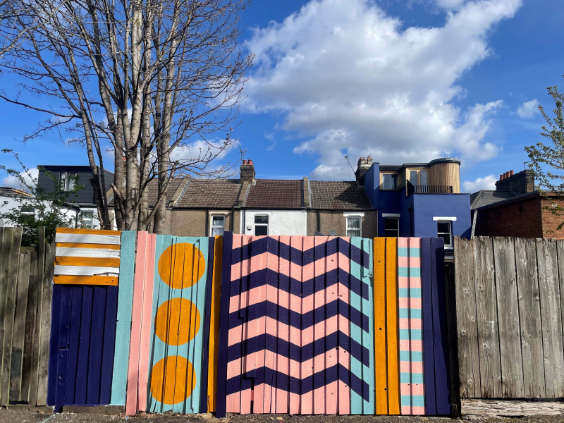 A wooden fence painted with a bright geometric pattern