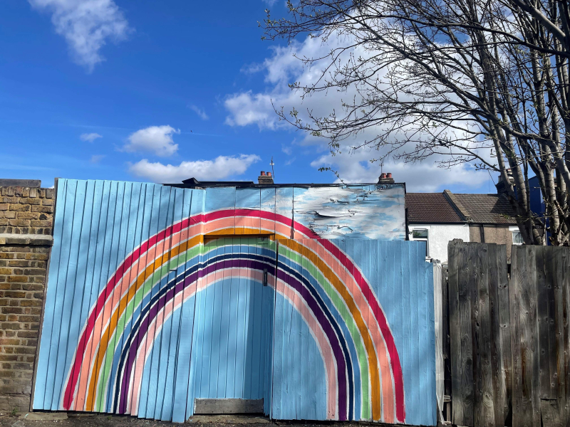 A wooden fence painted with a rainbow