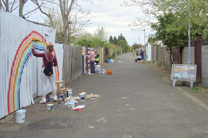 A wide shot of Carbuncle Passage in Tottenham, showing residents painting their back fences