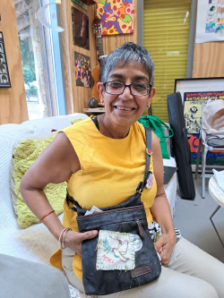 Ashika - a participant at Stitch Social smiling with the pouch she has stitched