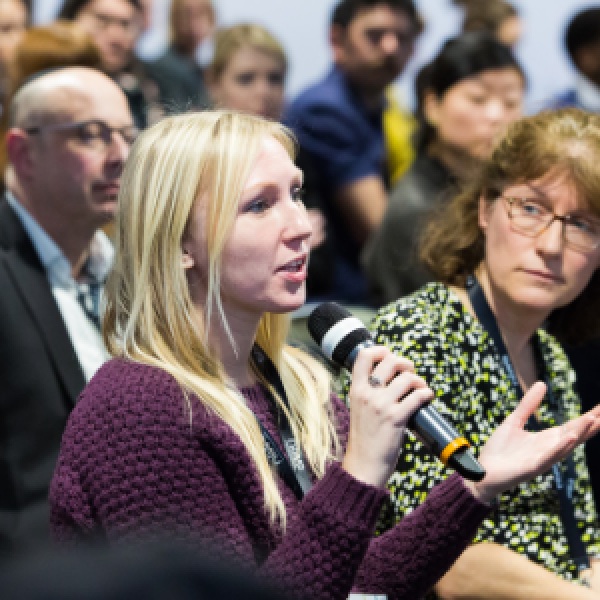 Blonde lady speaking into a microphone