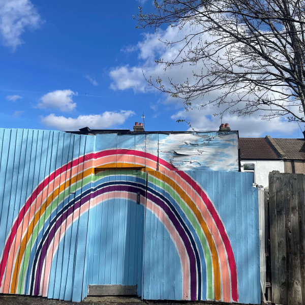 A rainbow painted onto a back fence