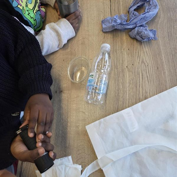 Students sorting recycling including tin cans, plastic bottle, and cardboard