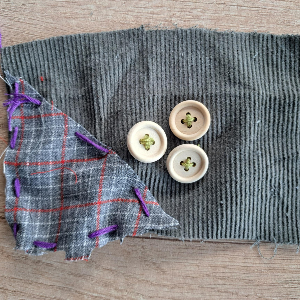 3 buttons and a patch sewn onto a piece of scrap fabric
