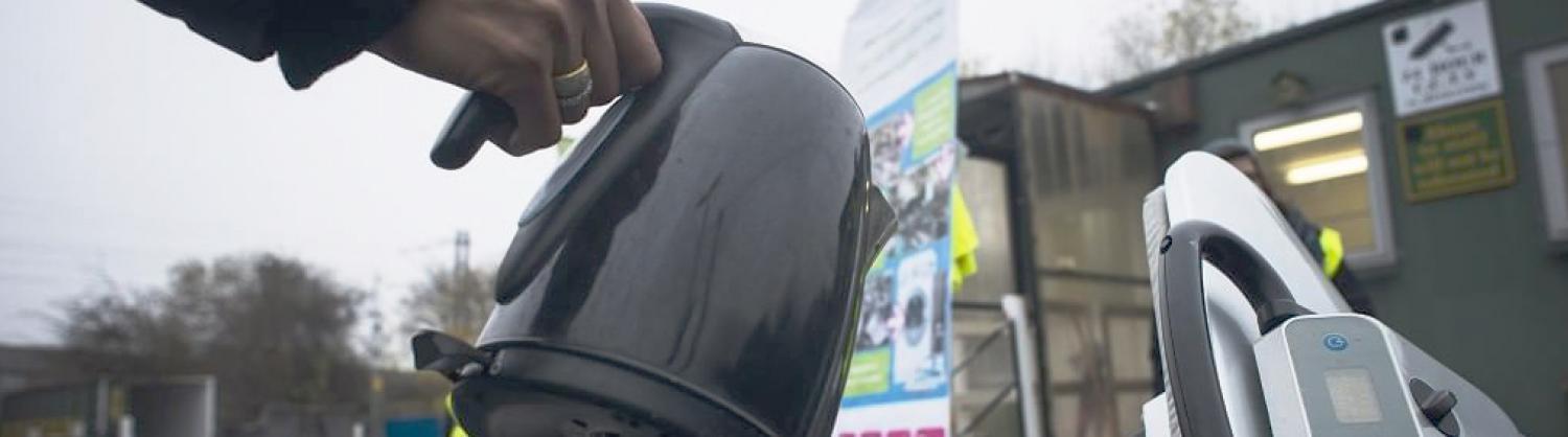 A kettle being placed in an electrical waste container.