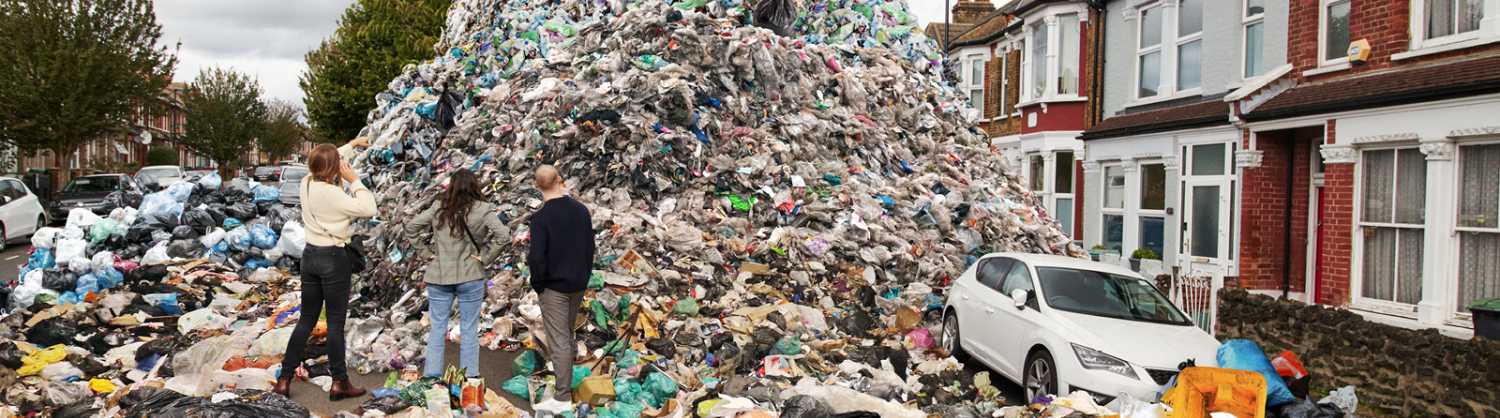 Three people looking at mountain of waste in street