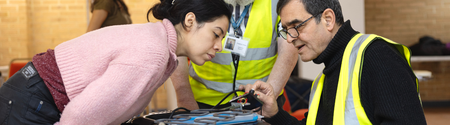 Repairers discussing an electrical repair at an event