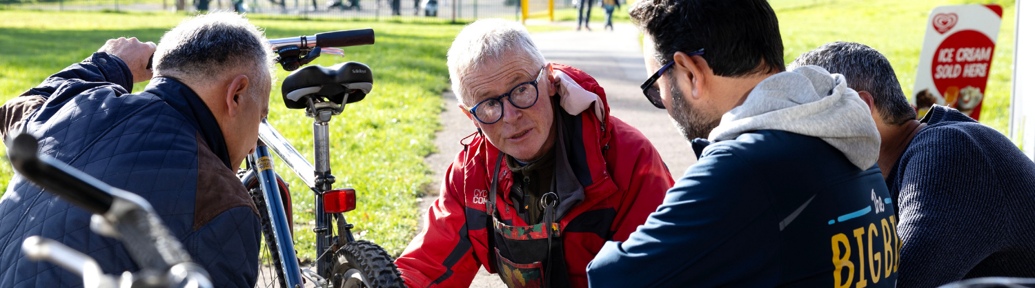 London Cycling Club volunteers knelt around a bike repair