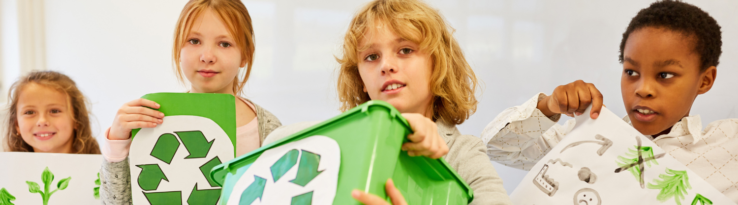 Four school children holding recycling boxes.