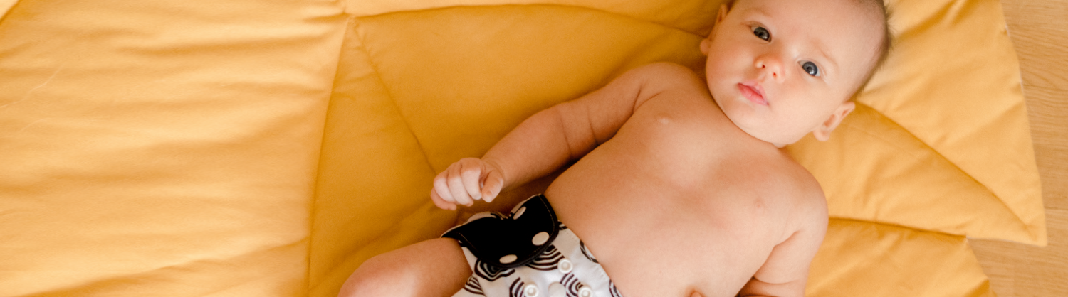 baby on bed wearing reusable nappy