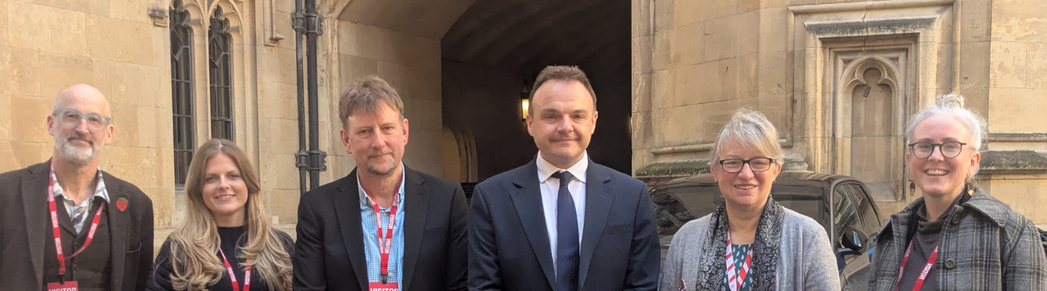 A group of people stand in front of the House of Lords building looking at the camera (attendees listed in text)