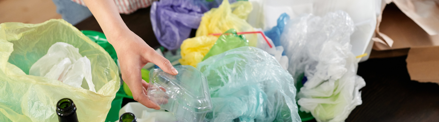 A woman holds a plastic tray, sorting it from other waste like plastic bags