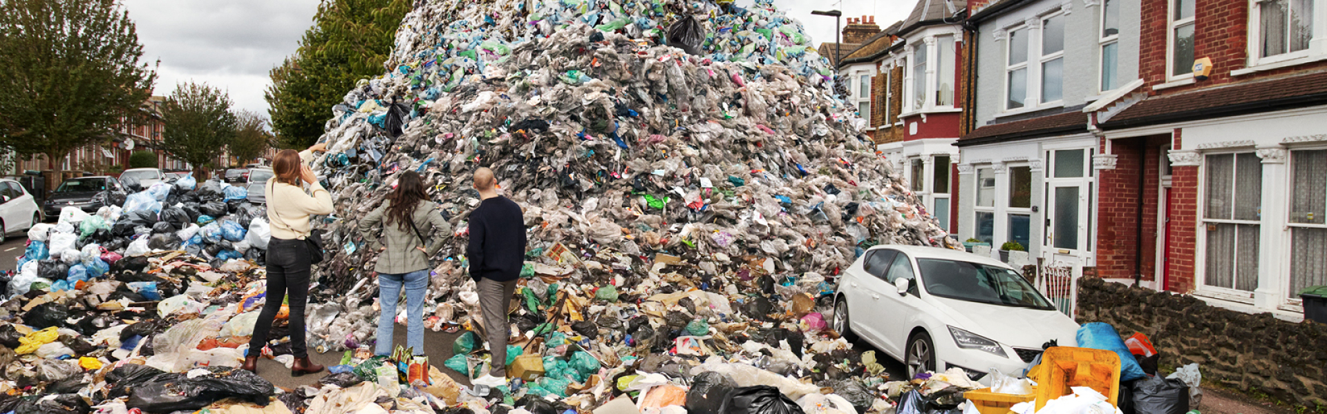 Mountain of waste in street and three people looking at it