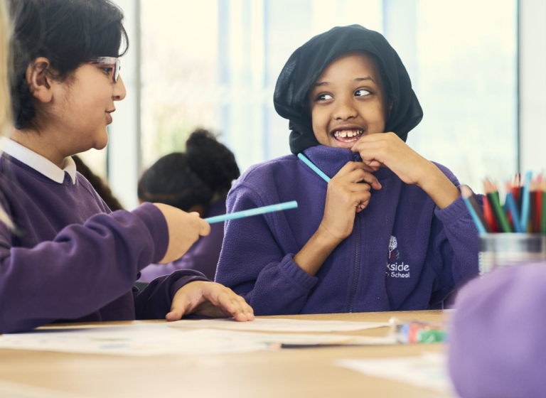 Two pupils smiling at eachother at EcoPark House