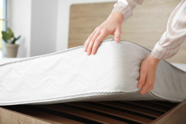 Person pulling a mattress up off bed frame