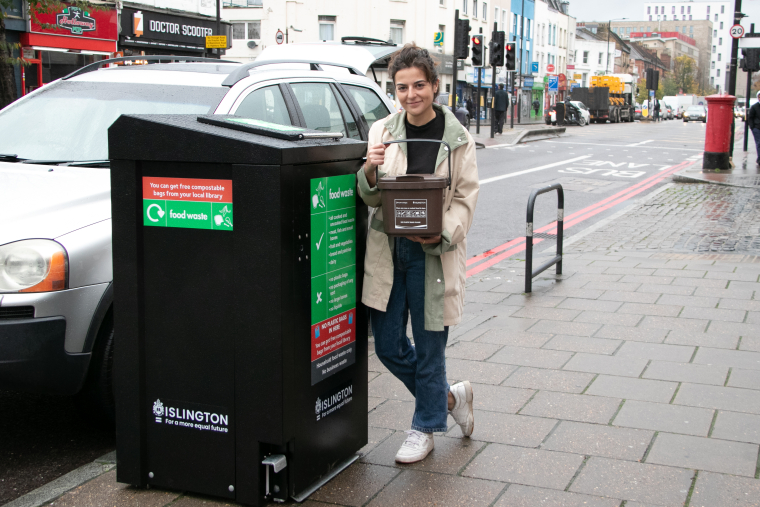 Islington resident, Noémie Bourguignon, with her new food waste caddy, beside one of the on-street designated bins along the Holloway Road.