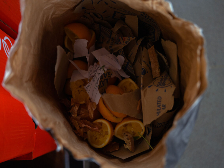 A paper bag with food and paper scraps in it