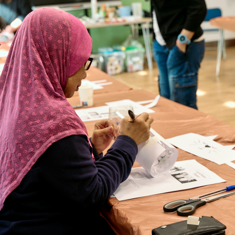 Attendee at the recycle art class at the first stage of making a planter from a plastic bottle 2024