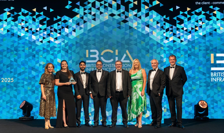 A group of people stand on-stage in front of an awards banner