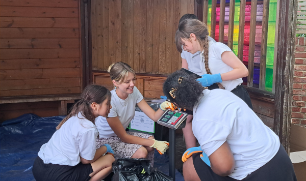 Schoolchildren and a woman weigh rubbish on a scale