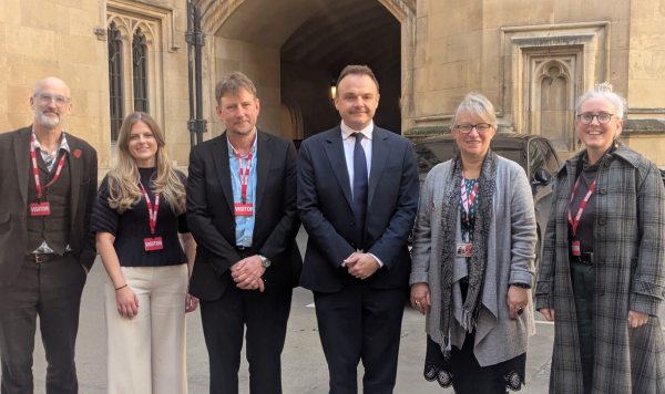 A group of people stand in front of the House of Lords building looking at the camera (attendees listed in text)