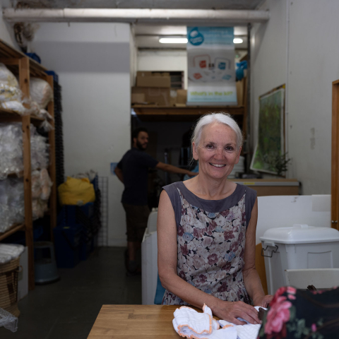 Image of person standing, smiling at the camera, folding reusable nappy