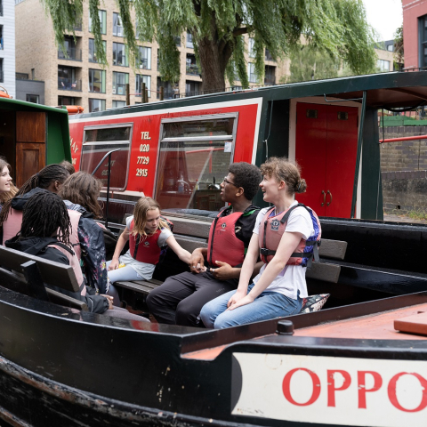 Image of four children sitting on a boat and talking