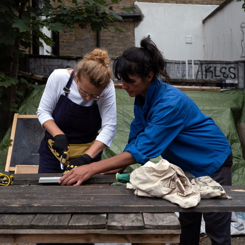 Image of two people working on a woodwork project outside