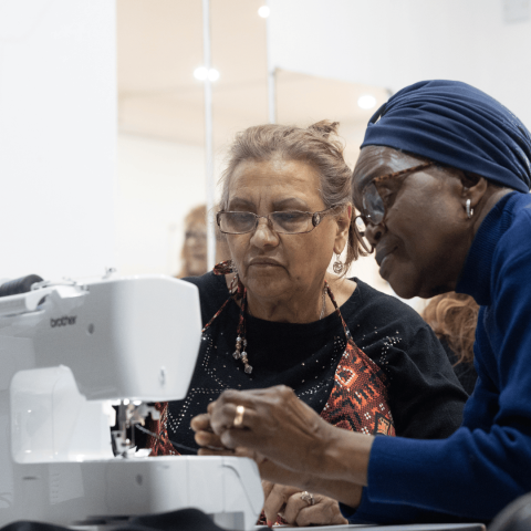 Two women working at a sewing machine at an Arachne workshop