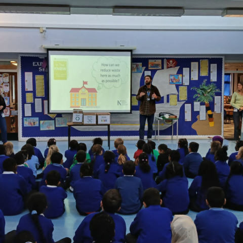 A group of pupils in a hall watching an assembly delivered by NLWA