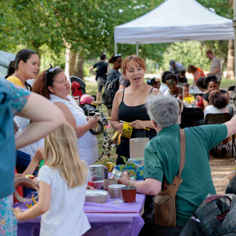 A man sits at a stall with people gathered around chatting