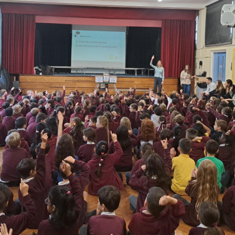 A group of pupils in a hall watching an assembly delivered by NLWA