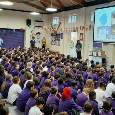 A group of pupils in a hall watching an assembly delivered by NLWA