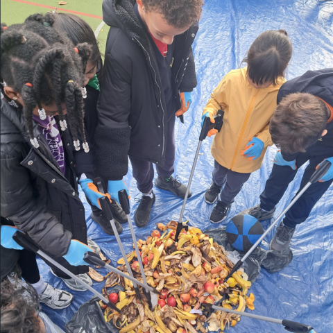 A group of students standing around a pile of food waste