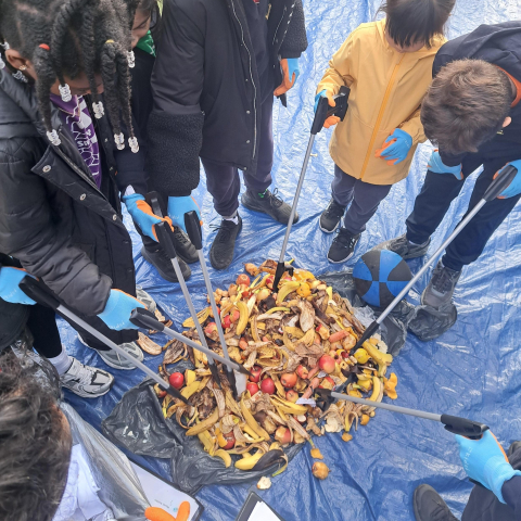 5 students looking at a pile of food waste
