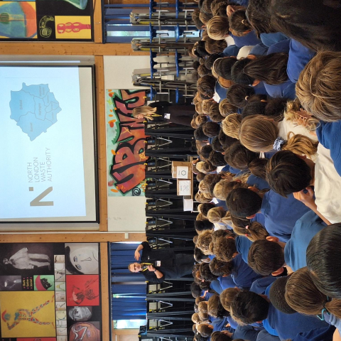 Backs of heads of students watching an assembly with a powerpoint