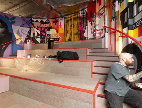 A man works on a colourful curved wall mural