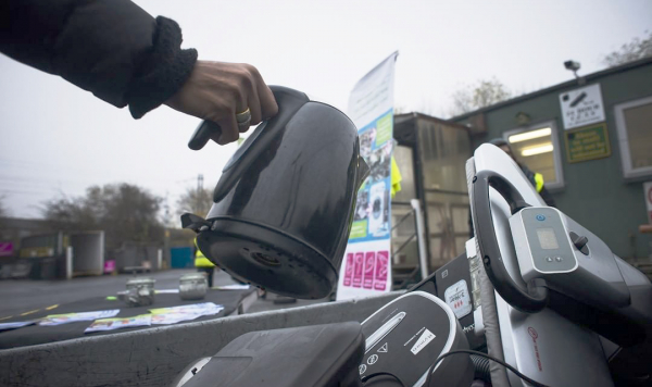 A kettle being placed in an electrical waste container.