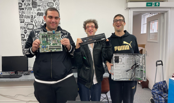 Three trainees holding parts of refurbished donated machines