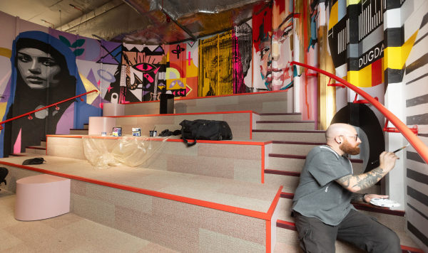 A man works on a colourful curved wall mural