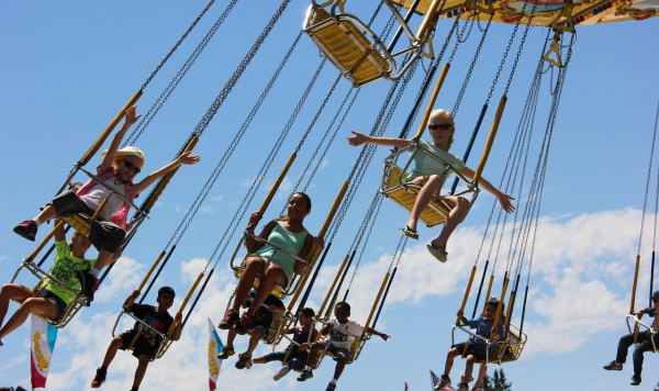 Children riding a fairground ride and waving